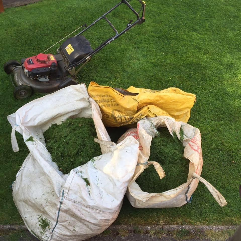 Push mower beside bags of grass clippings ready to be taken away
